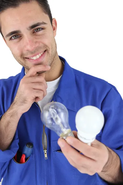 Joven electricista sonriendo sosteniendo bombillas —  Fotos de Stock
