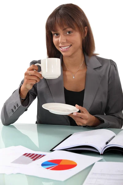 Женщина за чашкой кофе за своим столом — стоковое фото