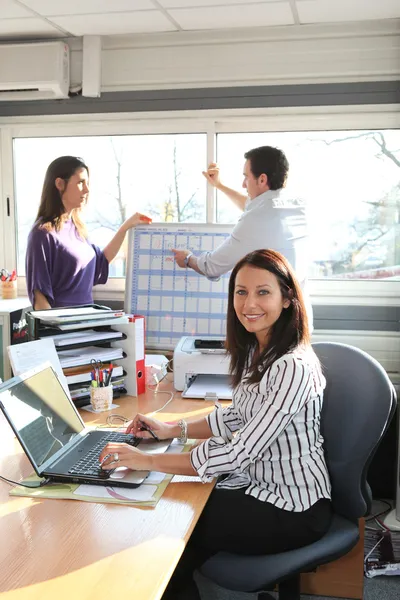 En kvinna på jobbet med kollegor — Stockfoto