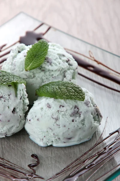 Tre palline di gelato con gocce di cioccolato alla menta su un piatto di vetro quadrato — Foto Stock