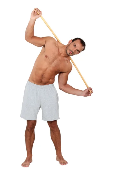 Uomo che si estende utilizzando palo di legno — Foto Stock