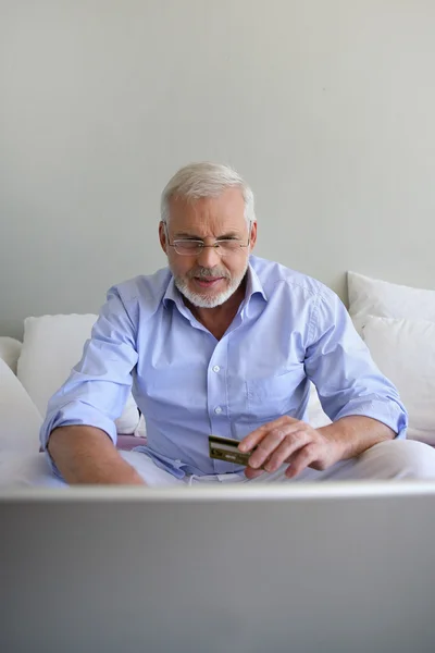 Homem sênior usando um cartão de crédito online — Fotografia de Stock