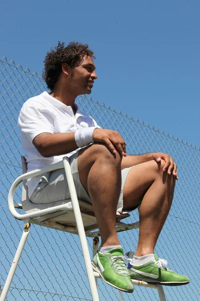 Портрет мужчины в спортивной одежде, сидящего в теннисном кресле судьи — стоковое фото