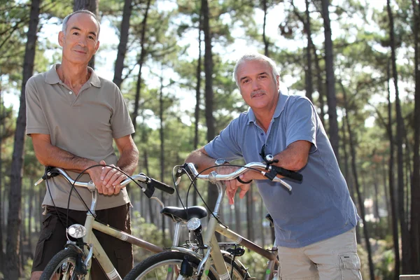 Старшие мужчины катаются на велосипеде по лесу — стоковое фото