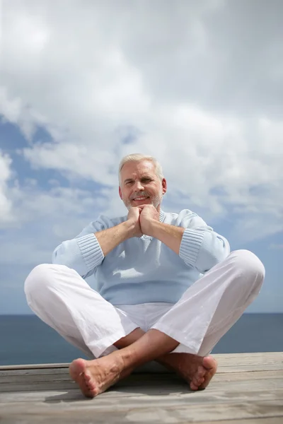 Senior man sat on a jetty — Stock Photo, Image
