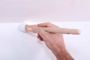 Closeup of a man cutting in a corner with white paint clipart