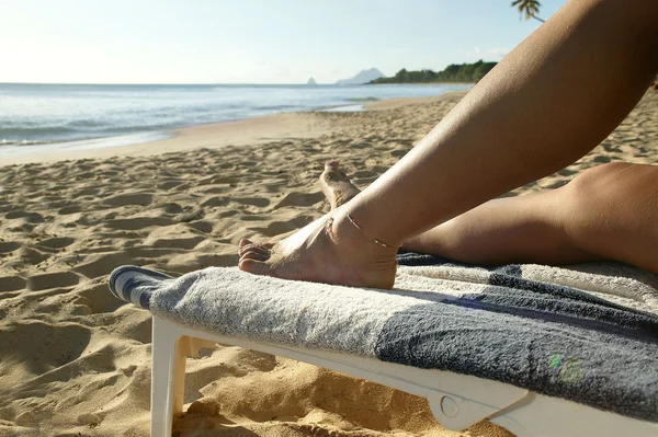 Женщина отдыхает на шезлонге на пляже — стоковое фото