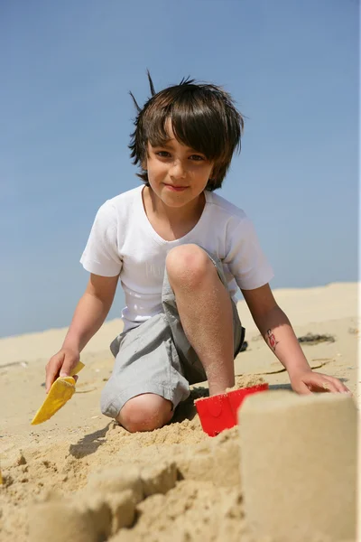 Liten pojke byggnad sand slott — Stockfoto