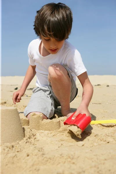 Menino construindo um castelo de areia — Fotografia de Stock