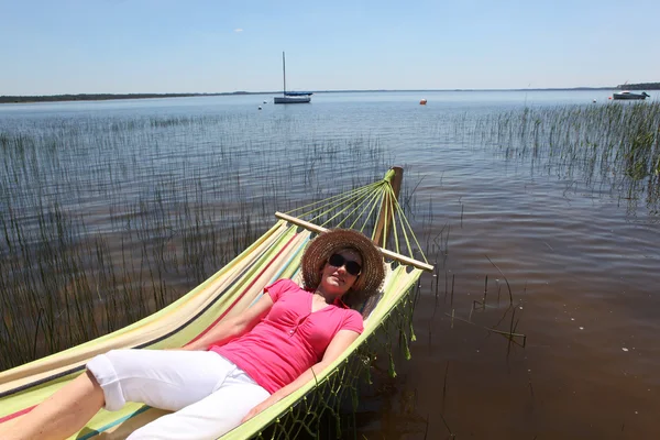 Vrouw in hangmat door lake — Stockfoto