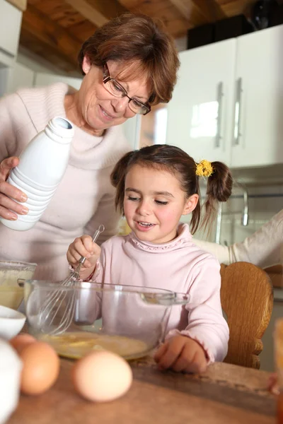 Ребенок помогает бабушке печь блинчики — стоковое фото