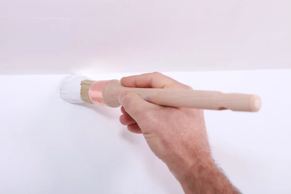 Fechar-se de um homem cortando em um canto com tinta branca — Fotografia de Stock