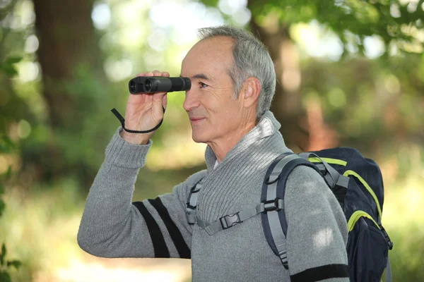 Senior backpacker looking through binoculars — Stock Photo, Image