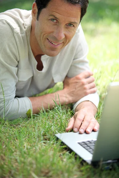 Homem sorrindo trabalhando na grama — Fotografia de Stock