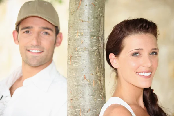 Young man and young woman near a tree — Stock Photo, Image