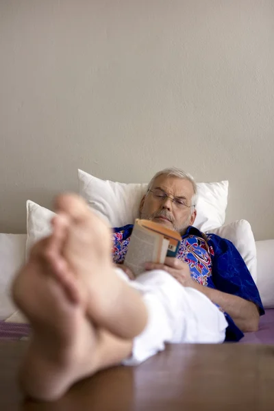 Старший читает книгу в постели — стоковое фото
