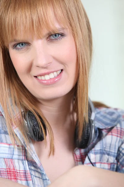 Mujer sonriente con un par de auriculares alrededor de su cuello — Foto de Stock