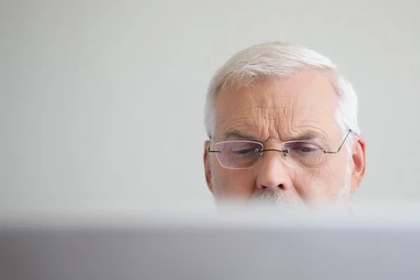 Старший чоловік дивиться на ноутбук — стокове фото