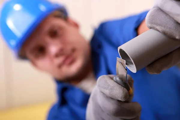 Encanador lixando a extremidade de um tubo — Fotografia de Stock