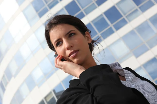 Junge Geschäftsfrau mit einem Handy vor einem Bürogebäude — Stockfoto