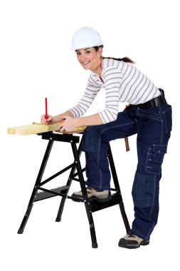 Tradeswoman marking a measurement on a wooden plank clipart