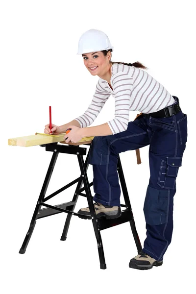 Tradeswoman märkning en mätning på en planka — Stockfoto