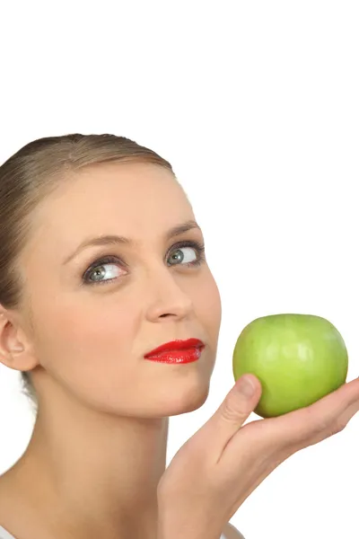 Женщина в красной помаде держит зеленое яблоко — стоковое фото