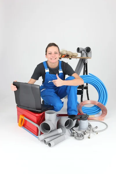Plombier femelle avec des outils du métier et un ordinateur portable — Photo