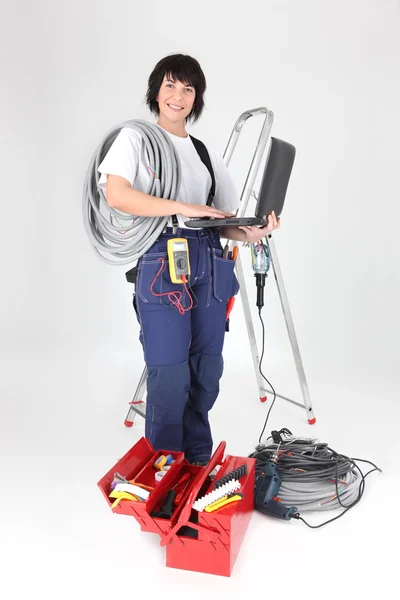 Etrafı ekipmanlarla çevrili kadın elektrikçi — Stok fotoğraf