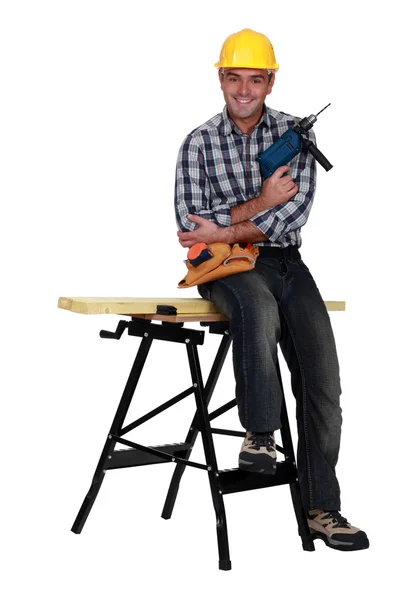 Человек с дрелью и рабочим столом — стоковое фото
