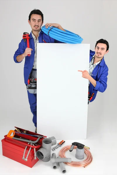 Klempner mit Werkzeug zeigt auf Brett — Stockfoto