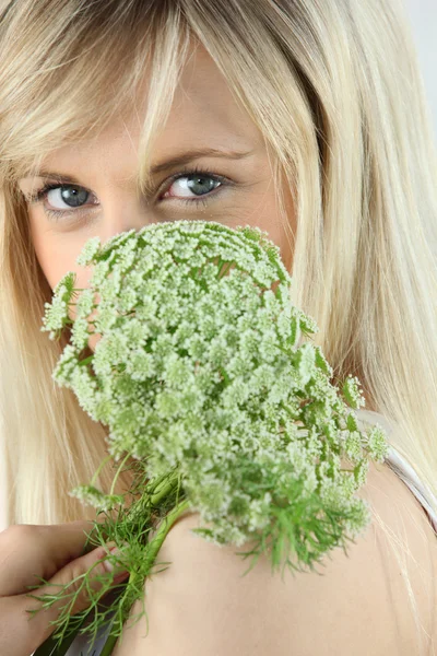 Close-up de uma mulher loira segurando uma flor verde na frente de seu rosto — Fotografia de Stock
