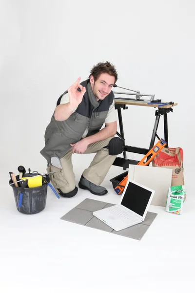Установщик плитки, позирующий со своими инструментами и строительными материалами — стоковое фото