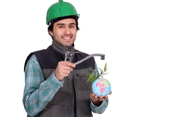 Man in a hard hap with a tap watering the world's plants — Stock Photo, Image