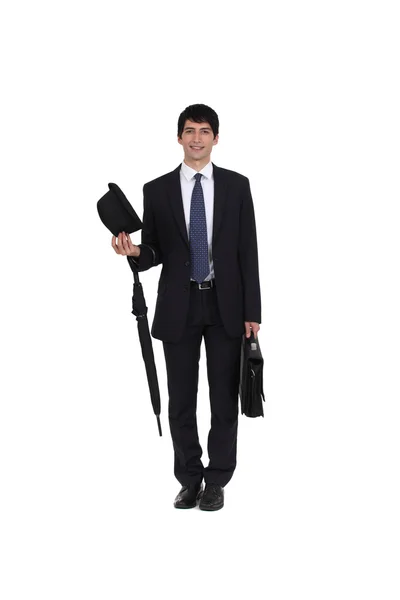 Businessman holding an umbrella, a briefcase and a hat — Stock Photo, Image