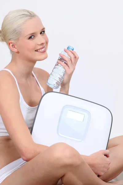 Mulher com uma garrafa de água e balanças eletrônicas — Fotografia de Stock