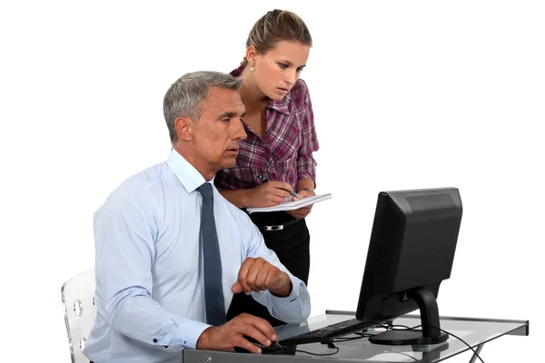 Zakenman in kantoor met computer en jonge vrouwelijke assistent — Stockfoto