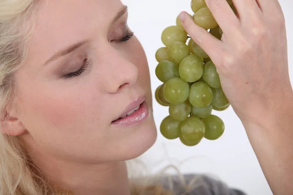 Mulher segurando um monte de uvas ao lado de sua cara — Fotografia de Stock