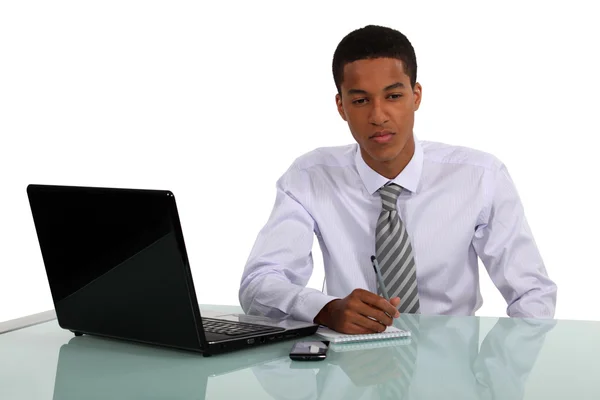 Man sat at desk writing on pad — Stock Photo, Image