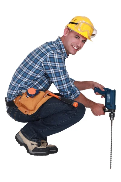 Tradesman using a power tool with a long bit — Stok fotoğraf