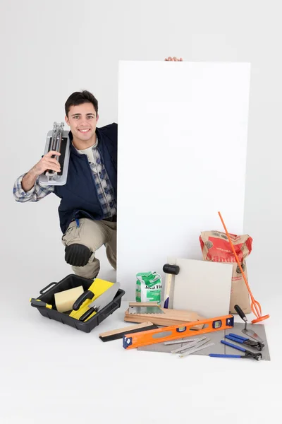 Comerciante posando con sus herramientas y un signo en blanco —  Fotos de Stock