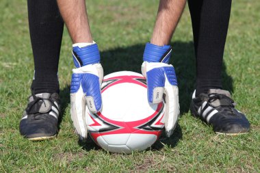 Closeup of goalkeepers hands placing ball on grass clipart