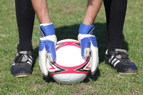 Närbild av målvakter händer att placera bollen på gräs — Stockfoto