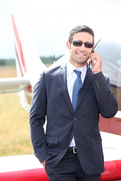 Förmögen affärsman framför ett flygplan — Stockfoto