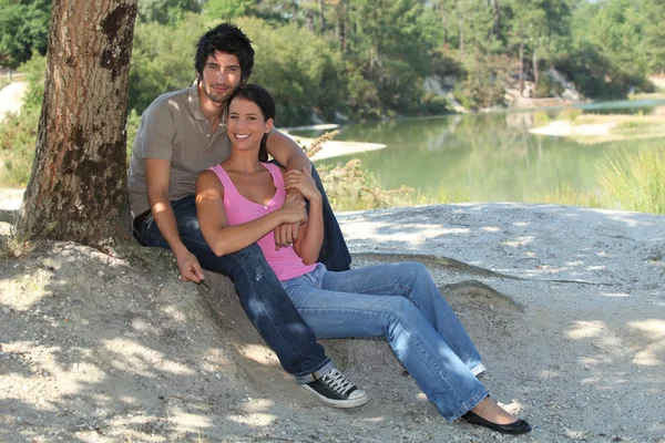 Молодая пара, сидящая у озера — стоковое фото
