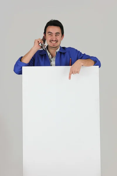 Artista masculino ficou com telefone celular na frente do quadro de mensagens em branco — Fotografia de Stock