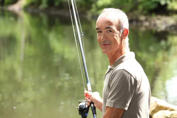 Homem sênior pesca perto de um lago — Fotografia de Stock