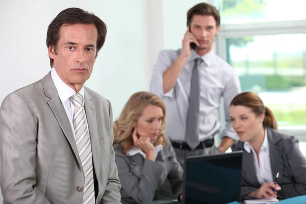 Businessman with colleagues in background — Stock Photo, Image