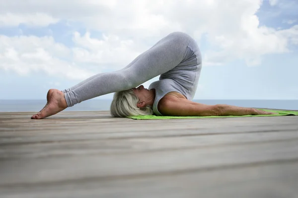 Senior woman doing yoga in a jetty — Stock Photo, Image