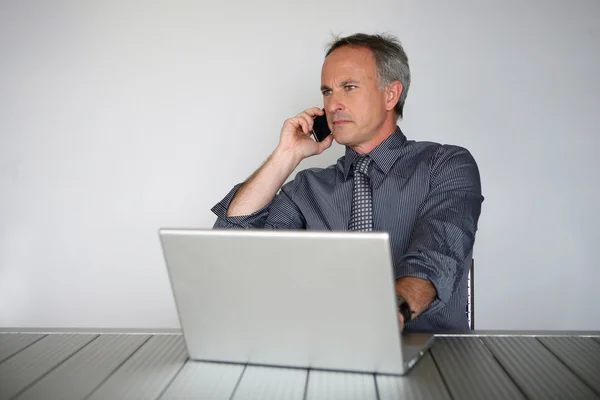 Homem com telefone e laptop — Fotografia de Stock
